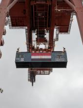 A shipping container with an Egypt flag banner hangs from a crane at Terminal 46 in Seattle.